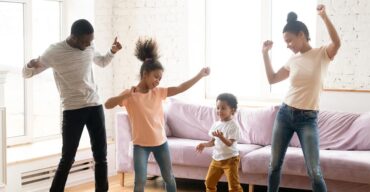 Pais e filhos dançando e mostrando uma das formas de como estimular a diversão em casa