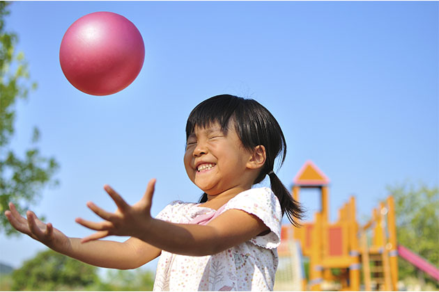 Vemos uma criança brincando com uma bola, brinquedo com para o desenvolvimento infantil.