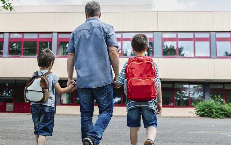 Pai levando crianças ao volta às aulas